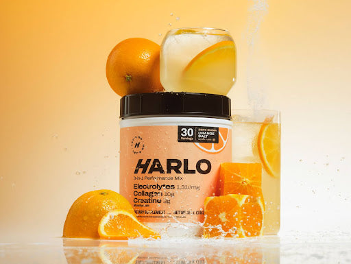 Harlo orange flavored electrolyte powder tub surrounded by fresh oranges, a clean drink for heart health, hydration, and recovery.